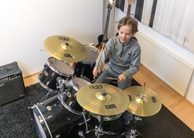 Nuori rumpujensoiton rumpali oppilas pitämässä hauskaa rumpujen kanssa musiikkikoulu PiaCellossa, Jyväskylä.